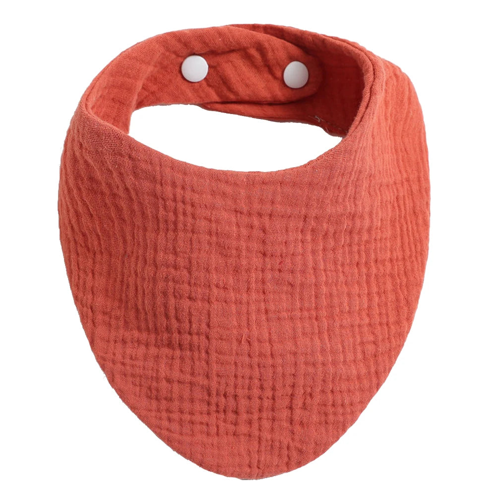 Un Bavoir lumineux 100% Coton pour Bébés de la marque BABY PREMA de couleur corail avec des boutons-pression réglables sur un fond blanc, un accessoire nécessaire pour l'hygiène
