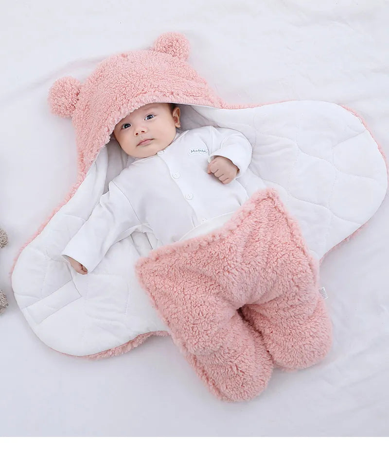 Un bébé serein vêtu d'une combinaison blanche avec un chapeau d'ours rose moelleux et des chaussons ours assortis, allongé sur une couverture matelassée blanche et douillette parmi BABY-PREMA Couverture Doux Bébé 0-9 mois | Protège en Toutes Saisons.