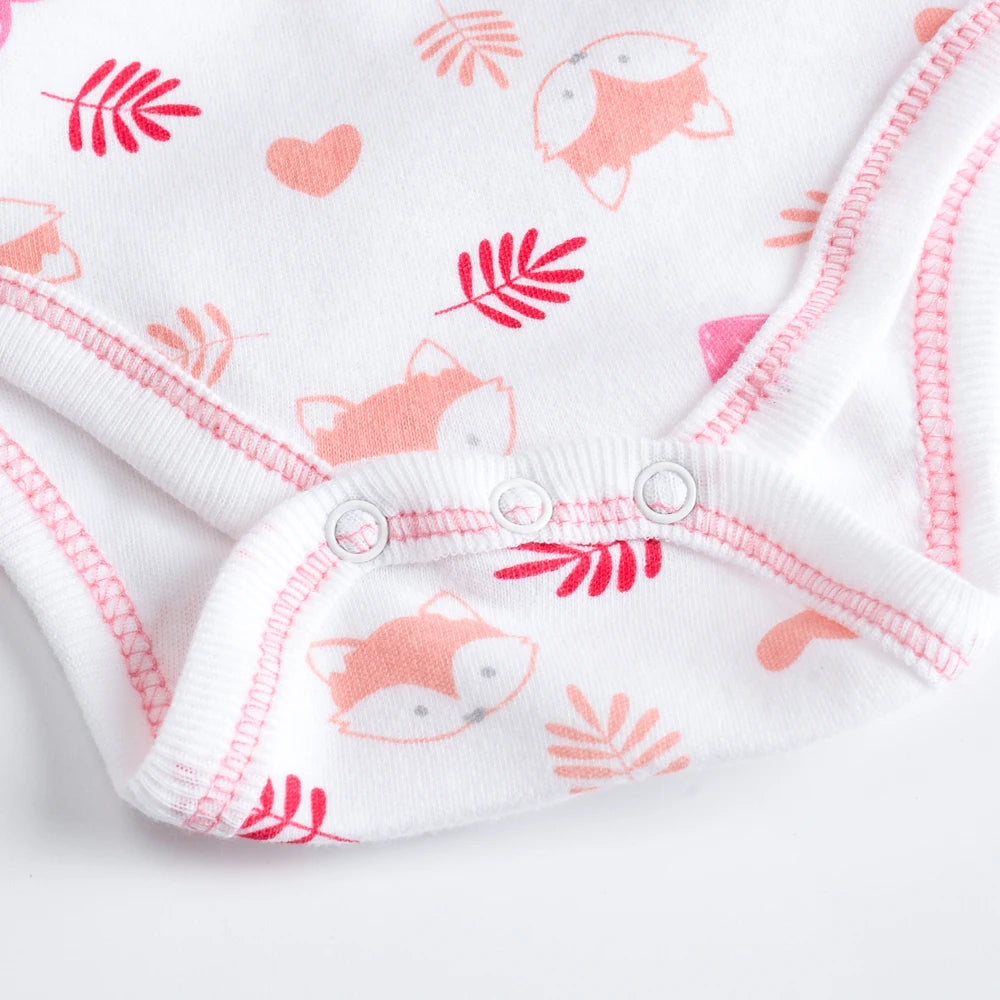 Un gros plan d'un Lot de 7 Bodies Bébé Imprimés Unis de BABY-PREMA blanc en coton doux avec des coutures roses, avec des imprimés de visages de renard, de feuilles et de cœurs dans des tons de rose et de rouge.