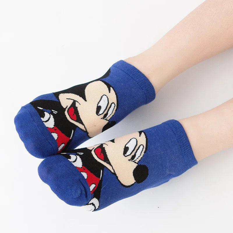 Deux pieds sont représentés portant des Paire Chaussettes Coton Coréennes bleues de BABY PREMA avec des personnages de dessins animés imprimés dessus. Les personnages ont de grands yeux, des nœuds papillon rouges et de larges sourires, ressemblant à un motif vintage de Mickey Mouse. Le fond est une surface blanche unie, mettant en valeur le toucher coton léger et confortable des chaussettes.