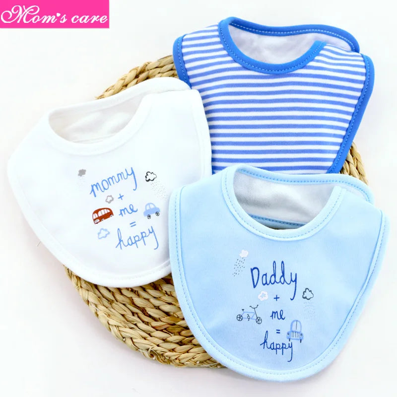Une photo de trois bavoirs pour bébé disposés sur un tapis rond tissé. L'un est blanc avec "maman + moi = heureux" brodé en bleu, un autre est bleu clair avec "Papa + moi = heureux" brodé en bleu et le troisième est rayé bleu et blanc. Ce Lot de 3 pièces Bavoirs Bébé de BABY-PREMA est confectionné en coton de haute qualité pour un confort ultime.
