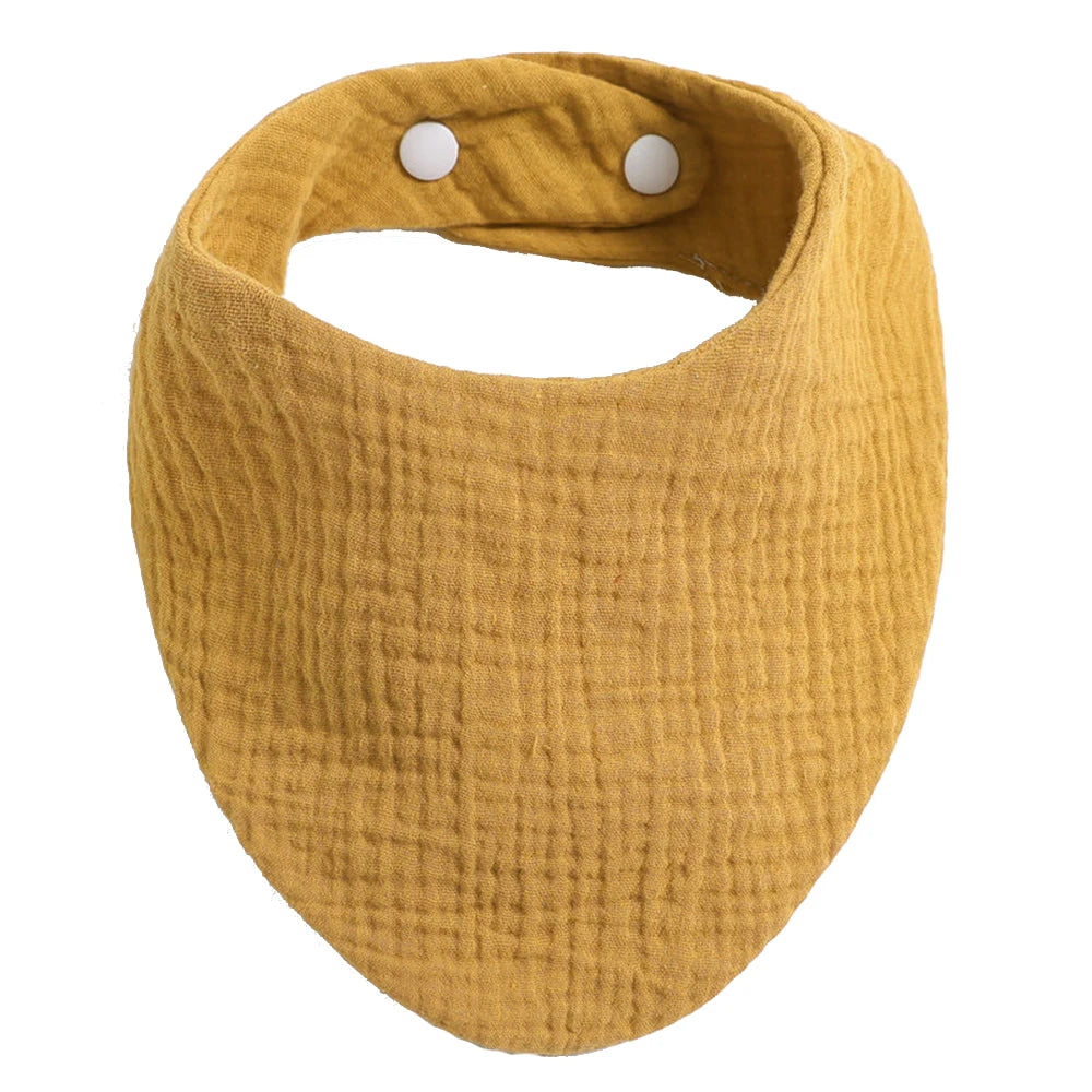 Une écharpe infini en tissu froissé jaune moutarde, conçue comme un accessoire Bavoir 100% Coton pour Bébés par BABY PREMA, avec deux boutons pression blancs visibles à une extrémité.