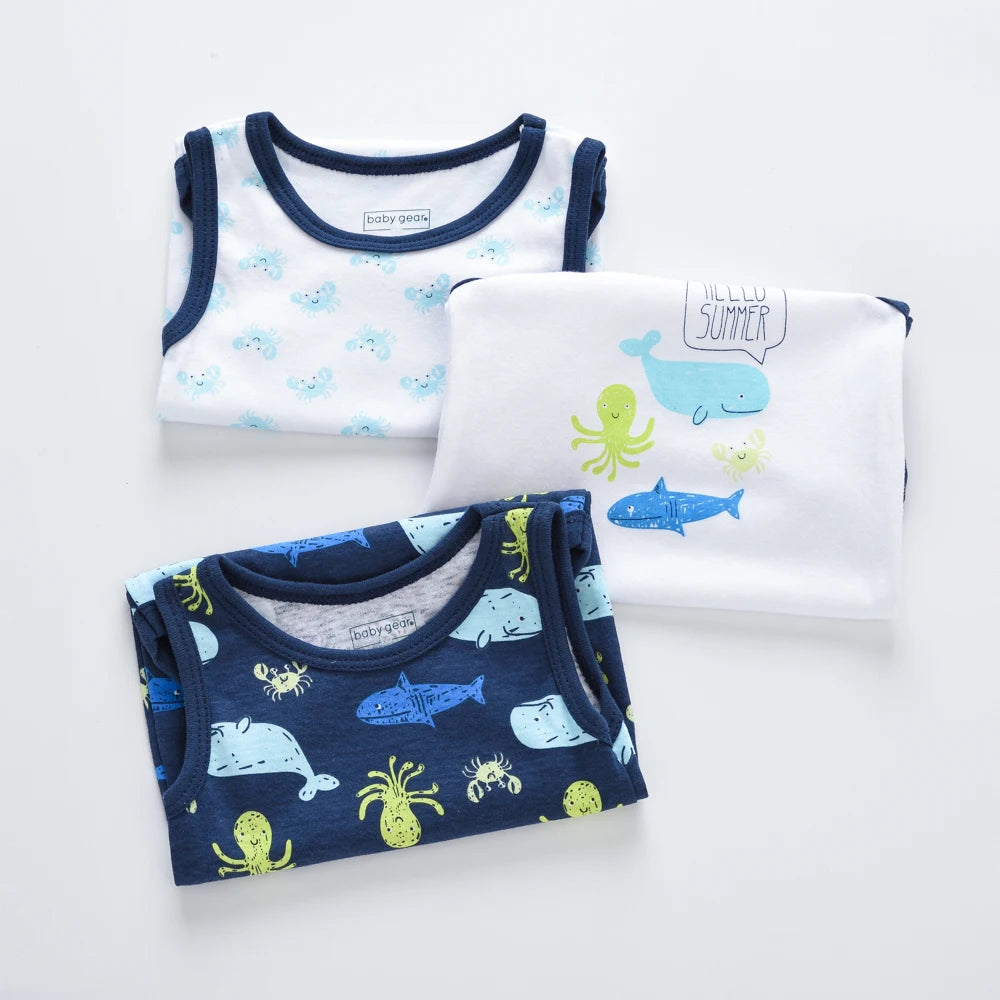 Lot de 3 Bodies bébé pliés de BABY PREMA avec des motifs sur le thème de l'océan, en coton doux et respirant. Celui du haut à gauche est blanc avec des crabes bleus, celui du milieu est blanc avec des animaux marins et le texte « Hello Summer », et celui du bas est bleu foncé avec des baleines, des poulpes et des crabes, parfait comme cadeau de baby shower.