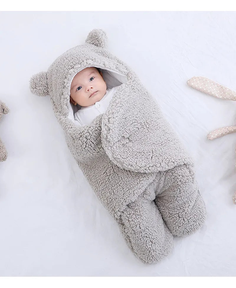 Un bébé douillet niché dans une gigoteuse douce sur le thème de l'ours, avec de petites oreilles sur la capuche, l'air content et bien au chaud. Cet adorable accessoire Couverture Doux Bébé 0-9 mois | Protège en Toutes Saisons garantit que votre tout-petit reste au chaud et à l'aise grâce à BABY-PREMA.