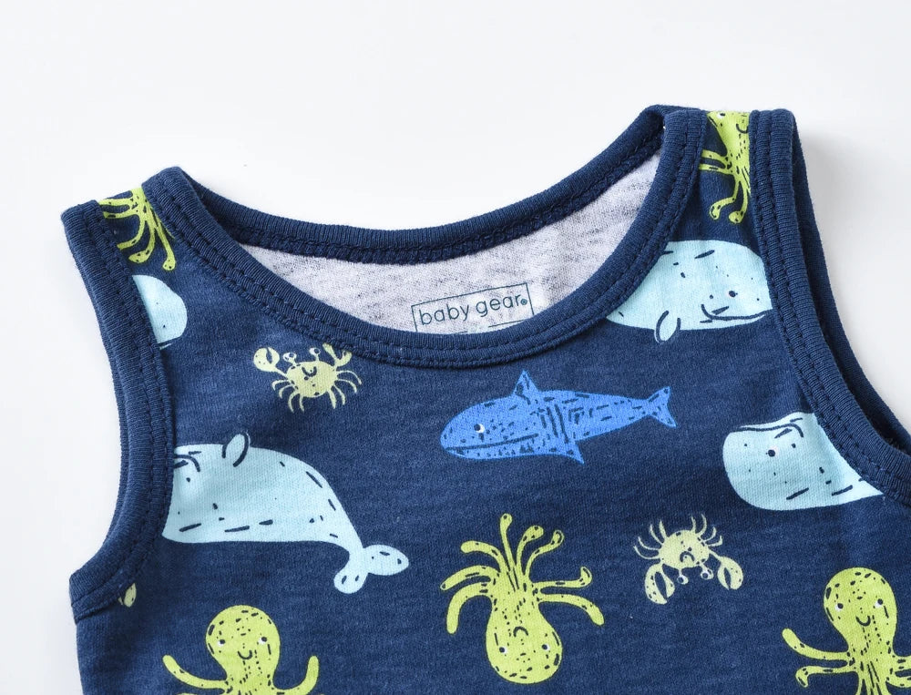 Un gros plan d'une chemise bleue sans manches pour enfant, comme une barboteuse sans manches, avec des animaux marins illustrés, notamment des baleines, des crabes, des requins et des poulpes dans des couleurs bleu clair et jaune. L'étiquette intérieure indique "Lot de 3 Bodies bébé" de BABY PREMA.