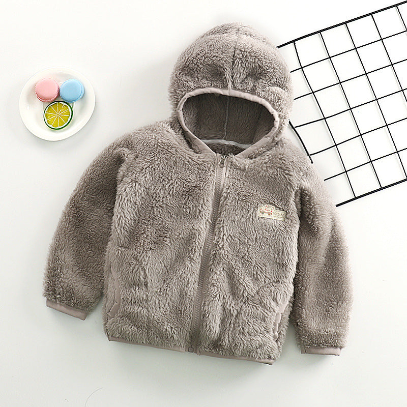 Gilet Veste pour bébé gris douillet de BABY PREMA avec une texture moelleuse et un joli patch ours sur un fond blanc épuré, accompagné d'une assiette colorée de tranches d'agrumes jouets.