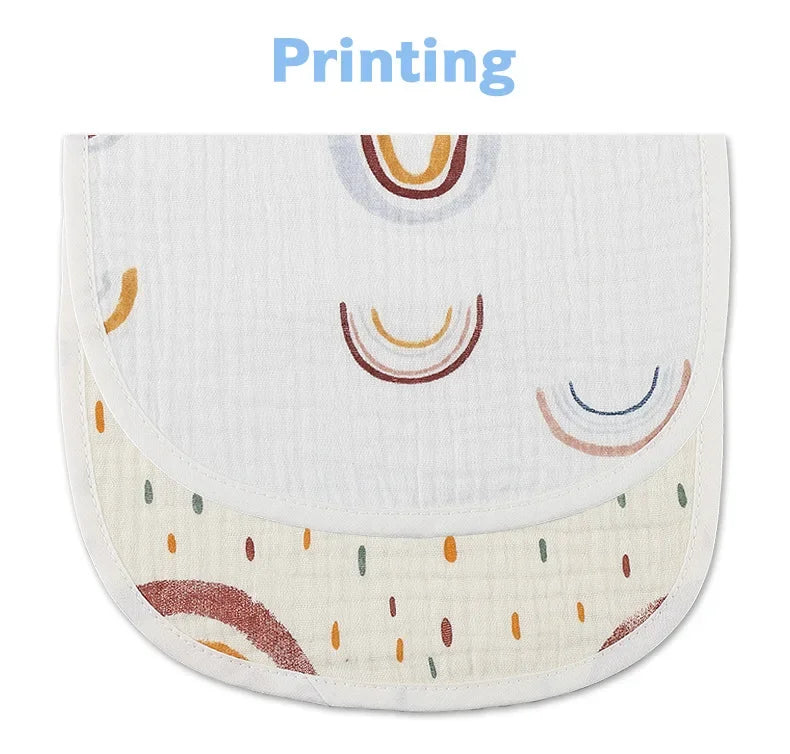 Un bavoir pour bébé de forme semi-circulaire, présentant des motifs arc-en-ciel et pois multicolores sur fond blanc. Le design style Bandana et le mot « Printing » sont imprimés en haut. Le produit s'appelle Bavoirs Motifs Bébé 2 Pièces de BABY-PREMA.