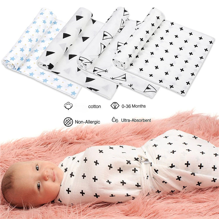 Un bébé paisible enveloppé dans une élégante couverture Baby Prema en Mousseline de Coton pour Bébé noire et blanche avec des motifs modernes, reposant sur une surface rose tendre, avec une collection de langes à motifs similaires soigneusement pliés à proximité. Les accessoires indiquent