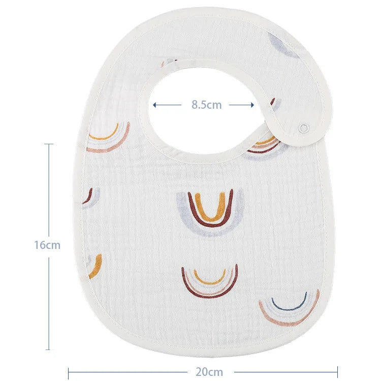 Un BABY-PREMA Bavoirs Motifs Bébé 2 Pièces blanc avec des motifs d'arcs colorés est présenté. Le bavoir, inspiré d'un bandana, possède une fermeture à pression et mesure 20 cm de large sur 16 cm de long, avec une ouverture de cou de 8,5 cm de diamètre.