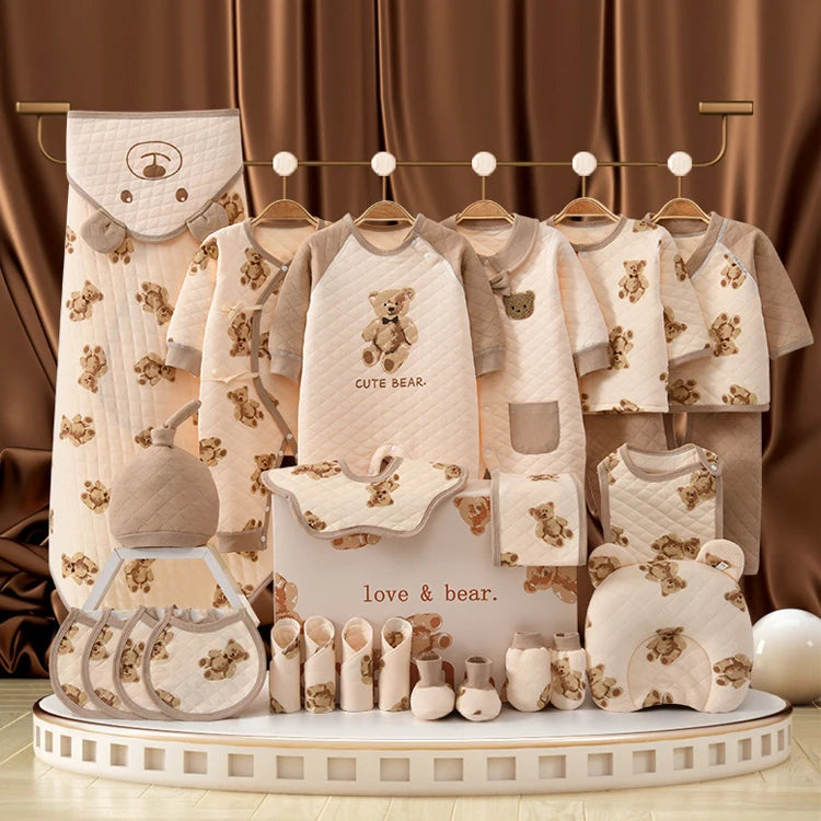 Un étalage de vêtements et accessoires pour bébé de BABY PREMA, avec des motifs d'ours, notamment des bavoirs, des grenouillères, des moufles et des couvertures, le tout en coton doux et respirant aux tons beiges et marron. Le texte sur l'étalage indique « CUTE BEAR » et « love & bear ». Kit complet de vêtements pour nouveau-nés Douceur Assurée.