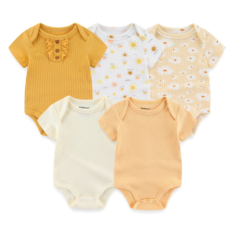 Cinq combinaisons assorties pour bébé sont exposées ; deux couleurs unies en jaune moutarde et crème, et trois à motifs représentant des soleils, des abeilles et des nuages. Ce Lot de 5 Bodys Bébé | Coton Agréables & conforts de BABY PREMA propose des bodys douillets en coton parfaits pour bébé.