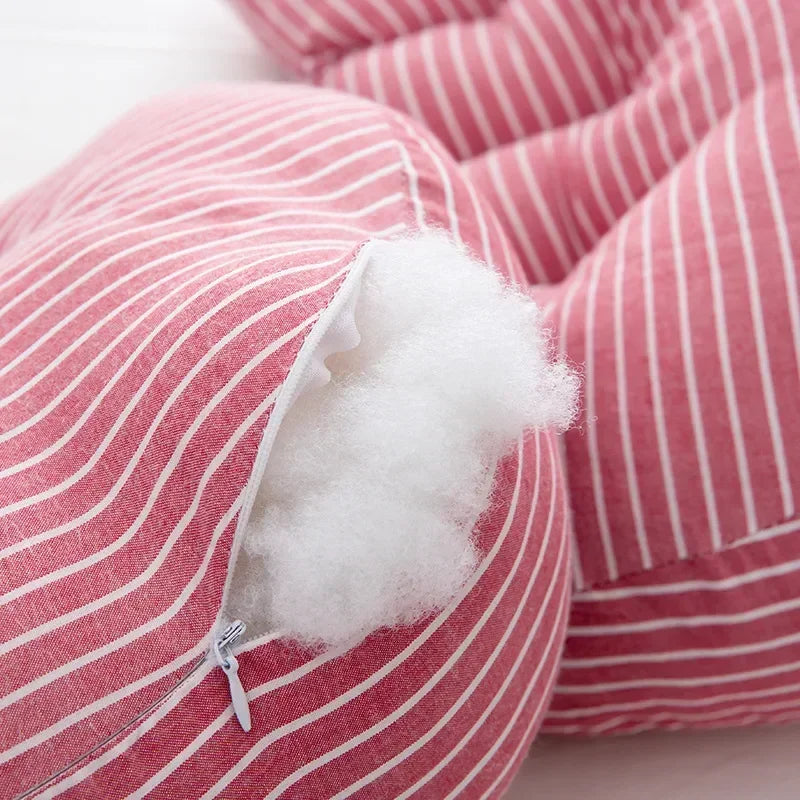 Gros plan d'un Oreiller de Grossesse en Coton rayé rouge et blanc avec une fermeture éclair visible partiellement ouverte, révélant un rembourrage blanc moelleux à l'intérieur. Le coussin semble être sur un fond à motifs similaire, offrant un soutien aux femmes enceintes avec style et confort. Le produit est de la marque BABY PREMA.