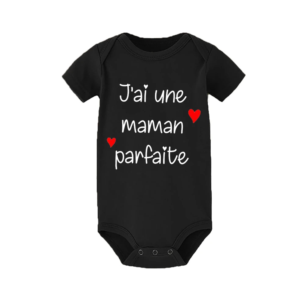 Un Body Bébé Coton Imprimé Préma noir de BABY-PREMA avec des manches courtes et un texte blanc qui dit « J'ai une maman parfaite », qui se traduit par « I have a perfect mom » en anglais. La combinaison comporte également deux petites illustrations de cœurs rouges, ce qui en fait un ajout charmant à toute garde-robe enfant.