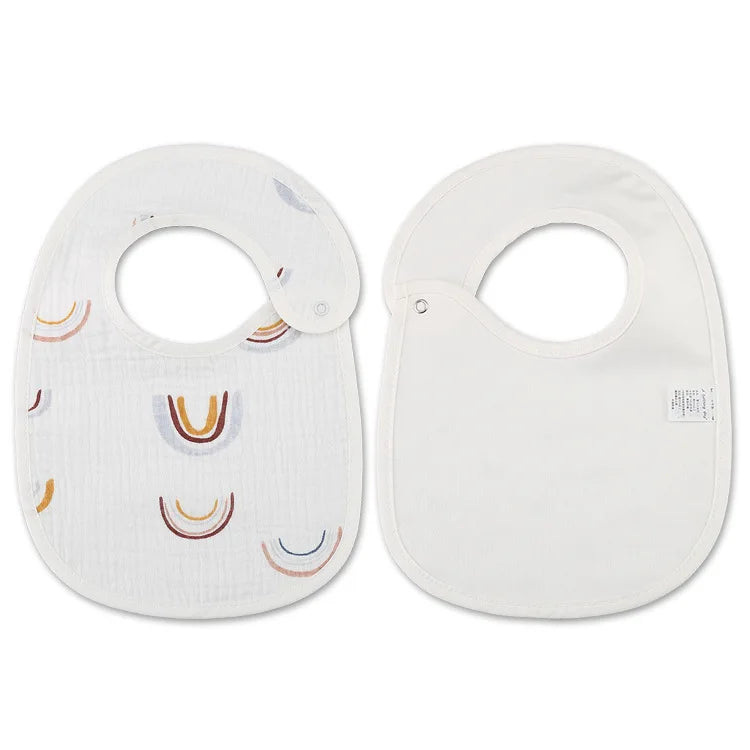 Deux BABY-PREMA Bavoirs Motifs Bébé 2 Pièces blancs, l'un avec des motifs arc-en-ciel colorés et l'autre uni, présentés côte à côte.