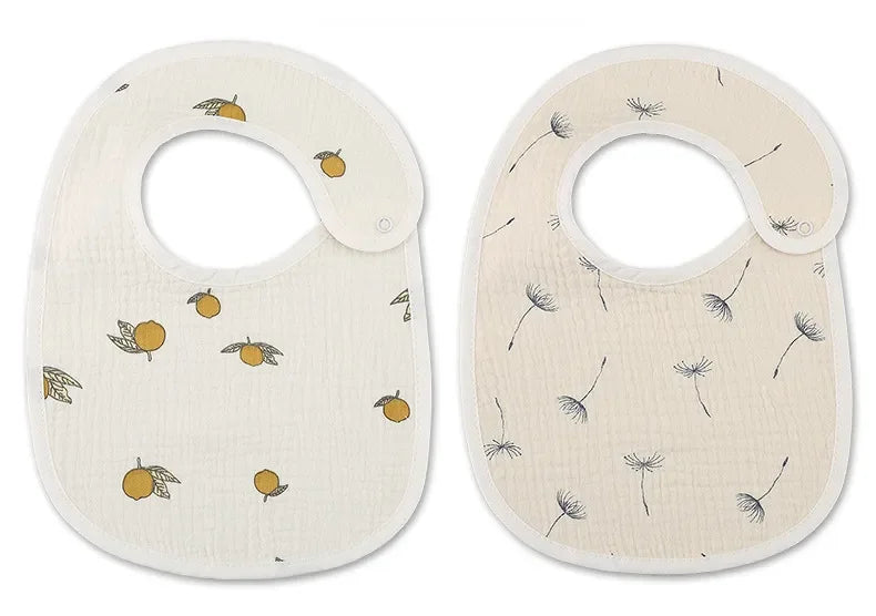 Deux bavoirs bébé sont exposés côte à côte. Le bavoir de gauche, un BABY-PREMA Bavoirs Motifs Bébé 2 Pièces, présente un motif de petits fruits oranges avec des feuilles vertes, tandis que le bavoir de droite présente un motif de graines de pissenlit éparses.