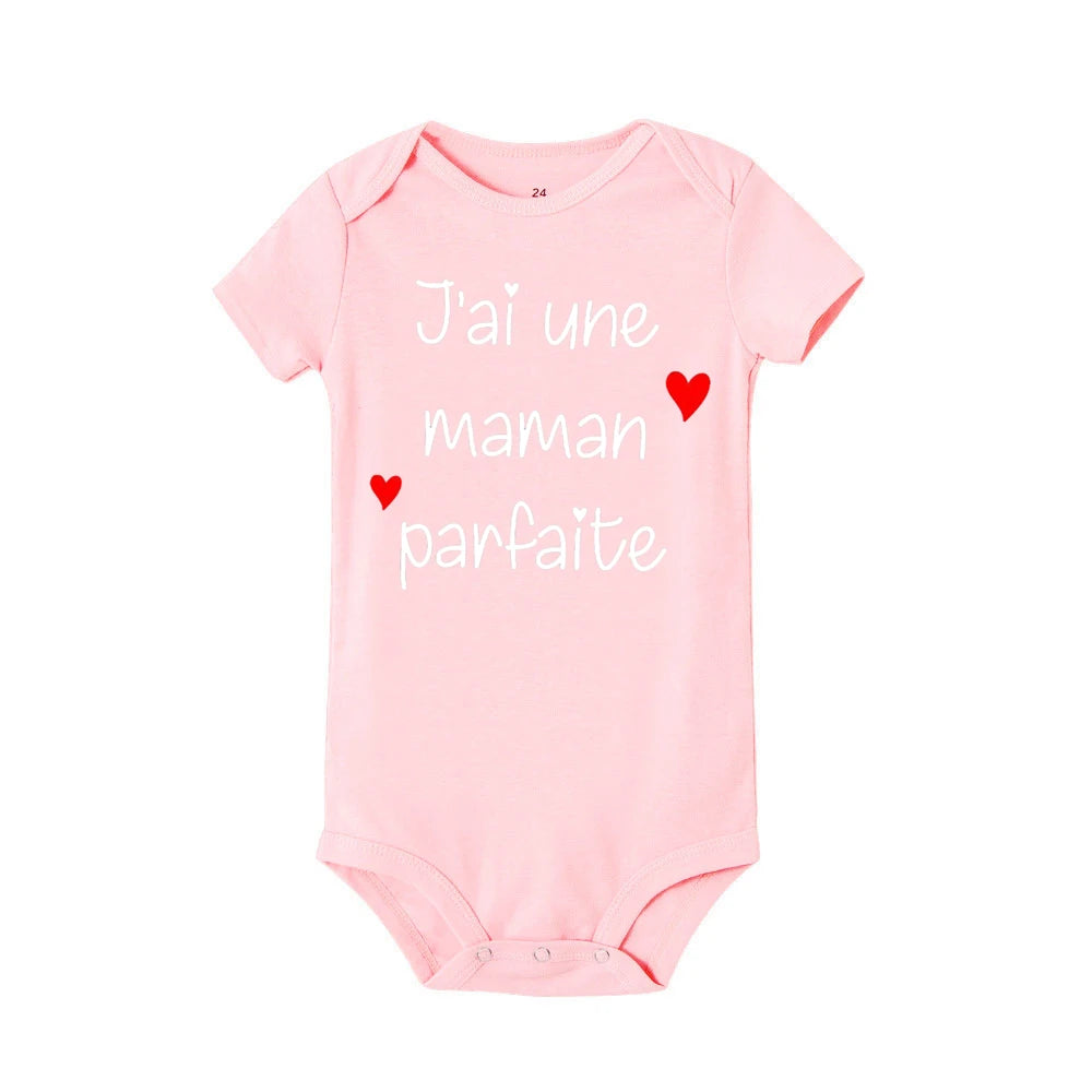 Un Body Bébé Coton Imprimé Préma rose de BABY-PREMA avec manches courtes comporte le texte français "J'ai une maman parfaite" et est orné de trois petits cœurs rouges, ce qui en fait un ajout charmant à toute garde-robe enfant.