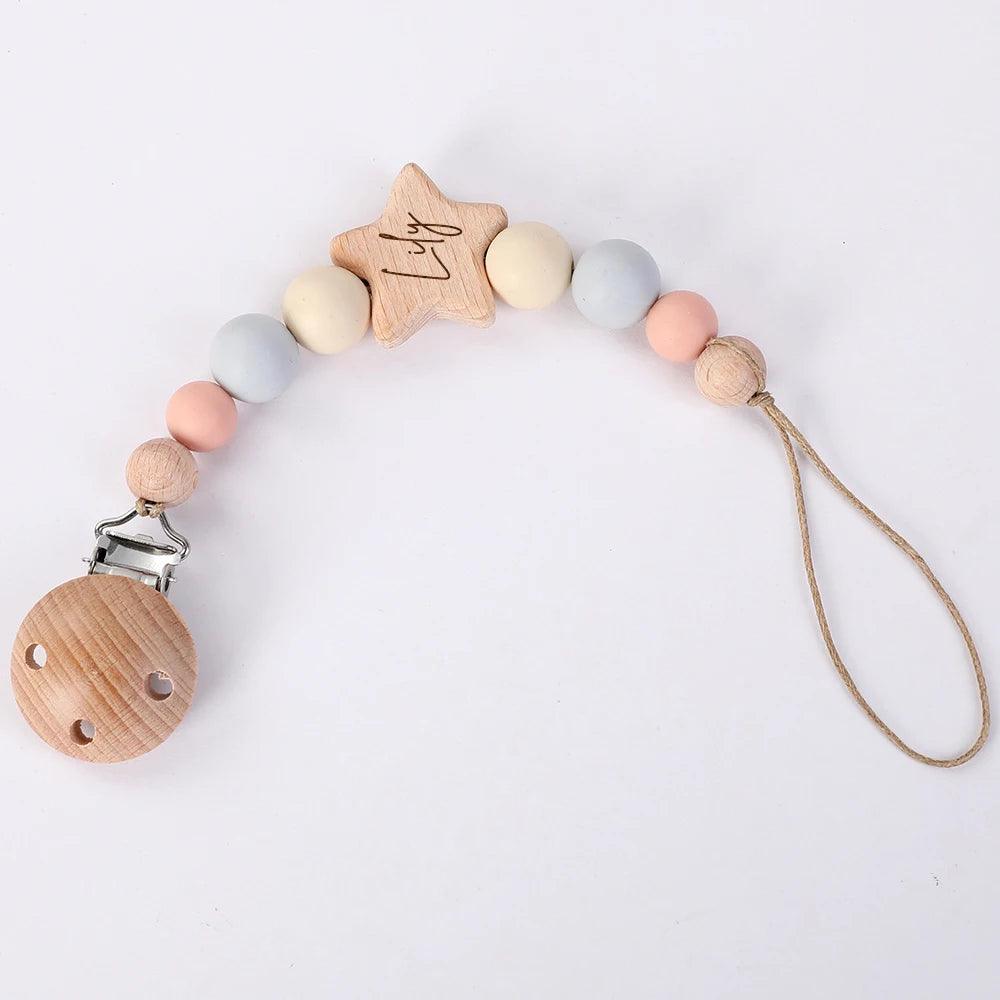 Accessoires bébé : Attache Sucette Bébé Personnalisée par BABY-PREMA avec des perles colorées et une pince en forme d'étoile sur fond blanc.