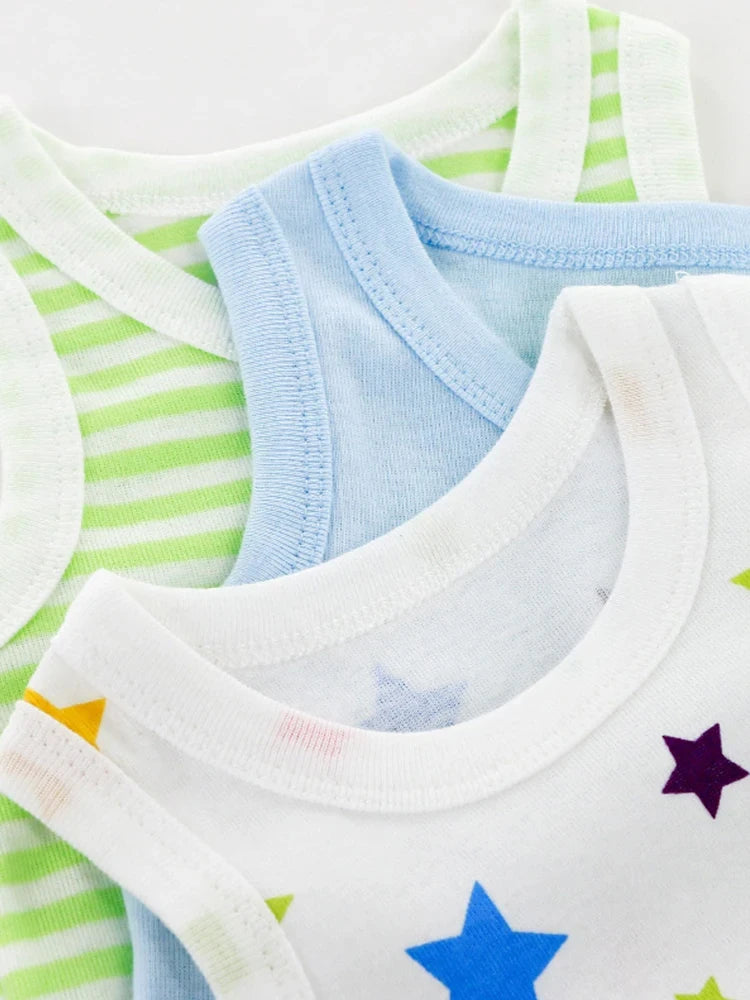 Trois Pack Cadeau 3 Bodies Bébé d'été, accessoires indispensables pour enfants de BABY PREMA, sont empilés, chacun visible depuis le décolleté. Celui du haut est blanc avec des étoiles colorées, celui du milieu est bleu clair et celui du bas est blanc avec des rayures vertes.