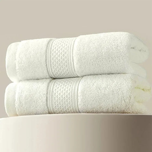 Serviette en Coton Forte pliée deux blanches | Absorption Douce de BABY PREMA avec des bandes décoratives sont empilées les unes sur les autres sur une surface lisse de couleur claire, mettant en valeur à la fois confort et durabilité.