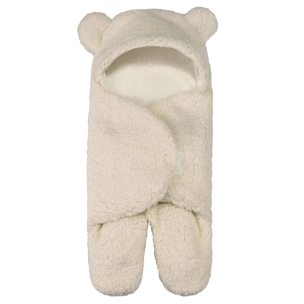 Une gigoteuse en peluche couleur crème avec une jolie capuche et des oreilles d'ours, un accessoire bébé indispensable pour le confort et l'hygiène, la Couverture Cocoon Nid d'Ange bébé de BABY PREMA.