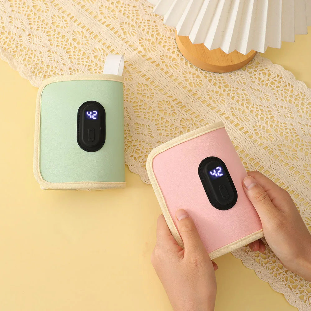 Deux petits appareils multifonctions Chauffe-Biberon Portable de BABY-PREMA, un vert et un rose, sont posés sur un chemin de table en dentelle sur une surface jaune. Les appareils affichent une température de 42°C sur leurs affichages numériques. Une paire de mains est représentée tenant l’appareil rose. Un abat-jour blanc est partiellement visible. Ces appareils portables et multifonctions peuvent également servir de chauffe-biberon.