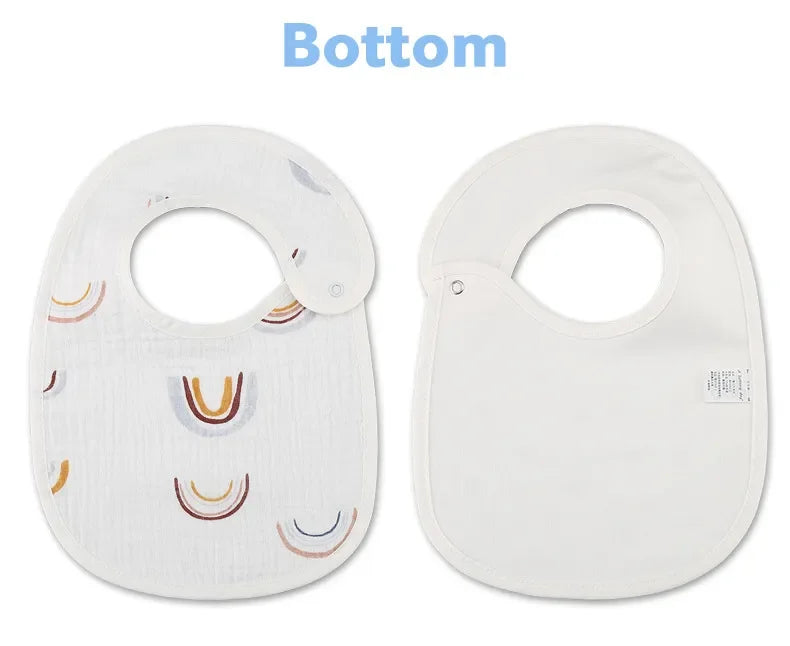 Deux bavoirs bébé sont présentés. Le bavoir de gauche a un motif arc-en-ciel et une fermeture à bouton-pression, tandis que celui de droite est blanc uni avec une étiquette et une fermeture à bouton-pression. Le mot « Bottom » est écrit au-dessus de ces Bavoirs Motifs Bébé 2 Pièces de BABY-PREMA.