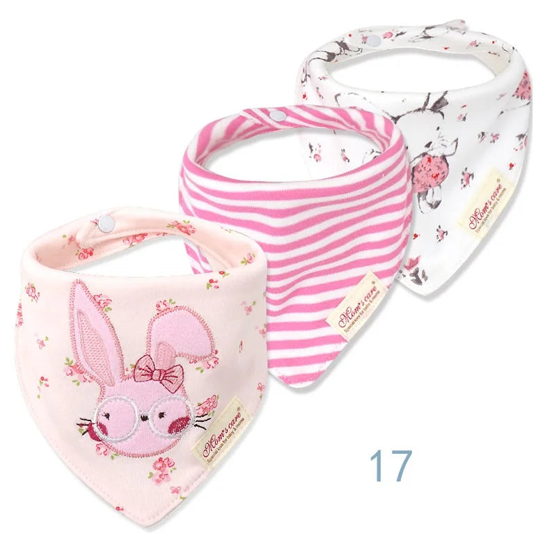 Trois bavoirs bébé sont exposés. Le premier bavoir bébé est rose clair avec un lapin brodé, le deuxième est rayé rose et blanc et le troisième est blanc avec un motif floral. Tous les bavoirs, fabriqués à partir de coton de haute qualité, portent une étiquette indiquant « BABY-PREMA ». Le chiffre 17 est affiché en dessous d'eux. Ce lot de 3 pièces Bavoirs Bébé présente des designs charmants parfaits pour tout petit.