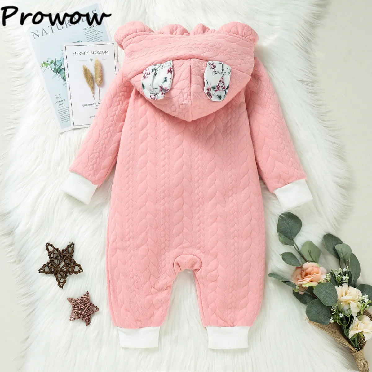 Un costume bébé rose sur surface fourrure blanche, parfait comme tenue d'hiver avec son modèle Combinaison pour Nouveau-nés de BABY PREMA.