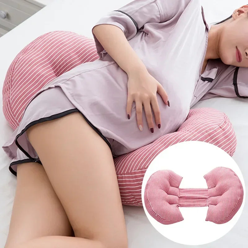 Une femme enceinte s'allonge sur le côté en utilisant un Oreiller de Grossesse en Coton spécialisé à rayures roses et blanches pour se soutenir. Elle porte une chemise de nuit violet clair, embrassant le nécessaire soutien aux femmes enceintes. Il y a une image en médaillon montrant un gros plan du design de l'oreiller par BABY PREMA.