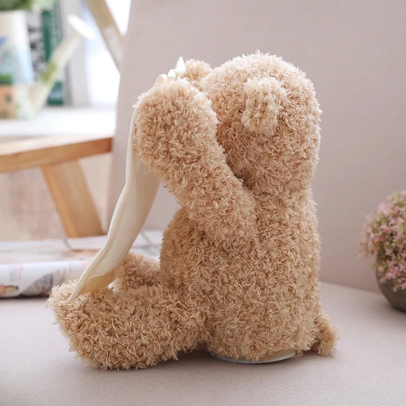 Un support téléphone Doudou Ours en Peluche posé sur une table, ses longues oreilles formant un berceau pour le téléphone, parfait pour le dodo d'un enfant.