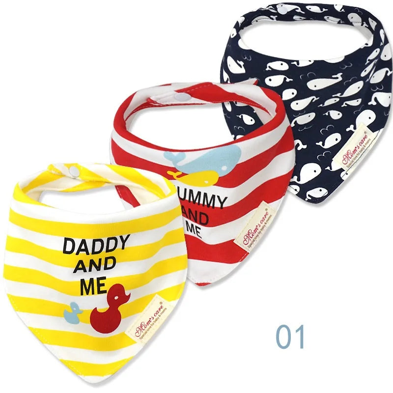 Trois bavoirs bandana pour bébé aux motifs assortis. Le bavoir jaune de gauche porte « PAPA ET MOI » avec un canard, le bavoir rouge du milieu porte « MAMAN ET MOI » avec une baleine et le bavoir bleu de droite présente un motif de baleines blanches. Tous les Lot de 3 pièces Bavoirs Bébé de BABY-PREMA sont fabriqués à partir de coton de haute qualité et sont dotés de fermetures à pression.