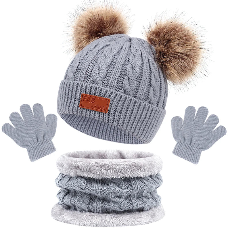 Ensemble chauffe-hiver BABY PREMA : bonnet tricoté gris confortable avec pompons moelleux, écharpe assortie et gants prêts pour l'enfant par temps froid.