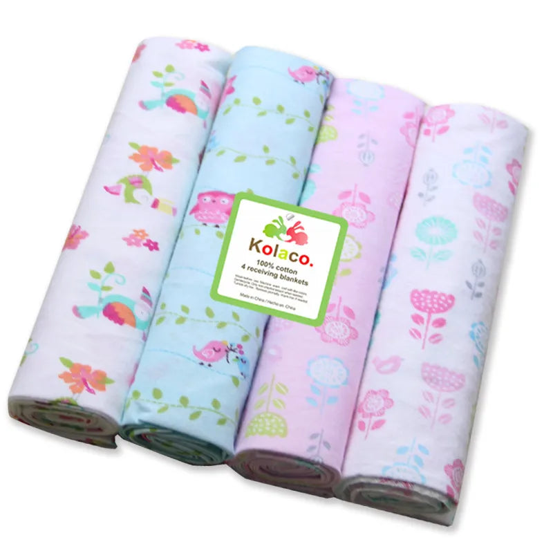 Quatre langes bébé en mousseline, avec des motifs pastel pour prématurés, présentés soigneusement côte à côte.