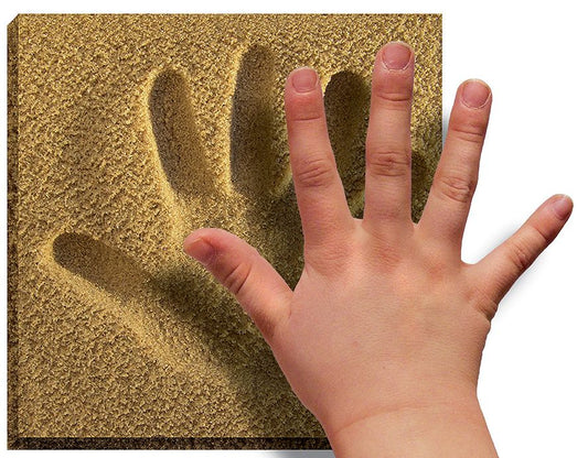 La main d'un enfant est placée sur l'empreinte d'une main plus grande sur une surface sablonneuse, montrant une comparaison de taille. L'empreinte sablonneuse texturée et détaillée, réalisée à partir de Sand Souvenirs - Emprunt Main - Licofun by LICOFUN, capture la forme et les contours des doigts et de la paume, ce qui en fait une pièce idéale pour des souvenirs créatifs ou une décoration unique.