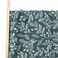 Élégant tissu vert avec un motif botanique à feuilles blanches drapé sur un cadre en bois léger de la couverture Lange d'Emmaillotage de BABY PREMA | 100% Coton pour Bébé.