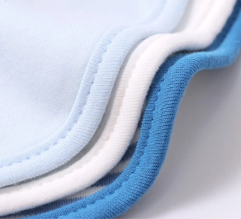 Image en gros plan de trois couches de bords de tissu, soigneusement empilées. Les tissus, parfaits pour le Lot de 3 pièces Bavoirs Bébé de BABY-PREMA, ont des bords bleu clair, blanc et bleu foncé. Les coutures et la texture lisse des tissus en coton sont clairement visibles, ce qui les rend idéaux comme accessoires pour bébés.