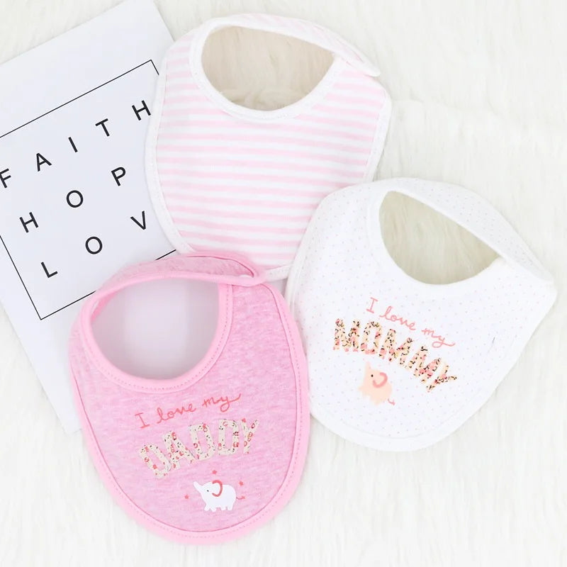 Trois bavoirs pour bébé sur une surface blanche et moelleuse. Un bavoir est rose avec "I love my DADDY" et un petit éléphant, un autre est blanc à pois et "I love my MOMMY", et le troisième est rose et rayé blanc. Ces adorables Lot de 3 pièces Bavoirs Bébé de BABY-PREMA sont des accessoires parfaits pour les bébés. Une carte avec "FOI, ESPOIR, AMOUR" est