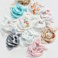 Une collection de turbans pour bébés doux et colorés avec divers motifs disposés en cercle sur fond blanc, conçus spécifiquement pour les bébés prématurés BABY PREMA.