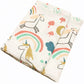 Une couverture pliée BABY PREMA Lange Bébé en Coton et Fibre de Bambou avec un motif ludique représentant des licornes, des arcs-en-ciel et des champignons sur fond blanc.