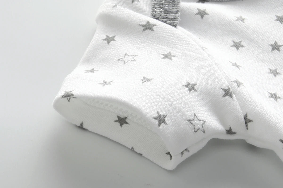 Gros plan sur un tissu blanc avec un motif de petites étoiles grises et un liseré gris, parfait pour BABY-PREMA Lot de 8 Bodies 100% Coton Bébé. La matière est 100 % en coton, assurant confort et douceur à votre tout-petit.