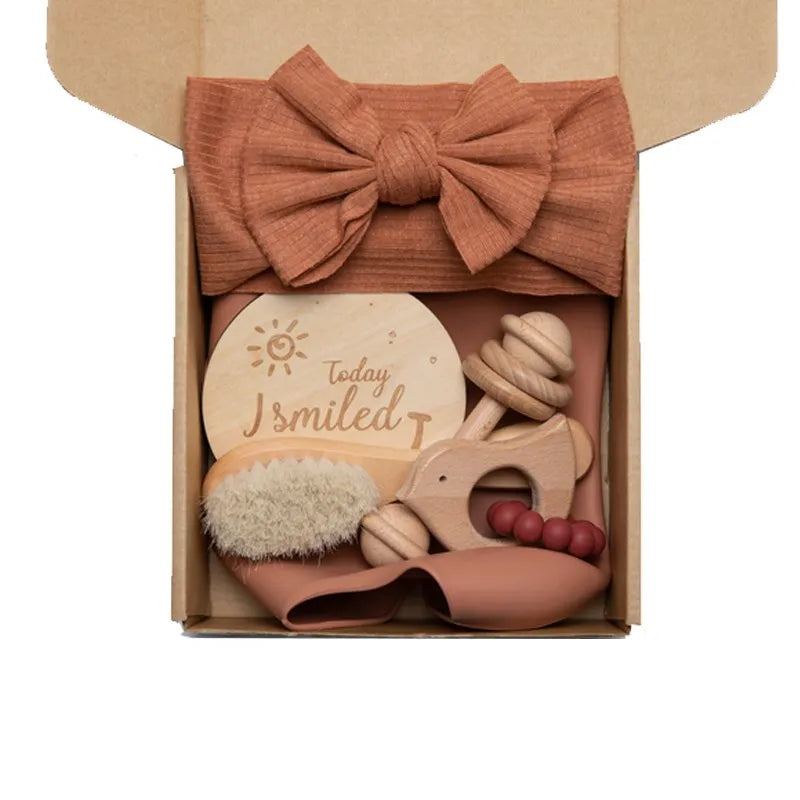 Un charmant coffret cadeau Coffret Cadeau Naissance Bébé soigneusement emballé dans une boîte en carton, comprenant des jouets en bois, des accessoires bébé et une plaque circulaire en bois avec l'inscription "aujourd'hui j'ai souri", le tout attaché ensemble avec BABY PREMA.