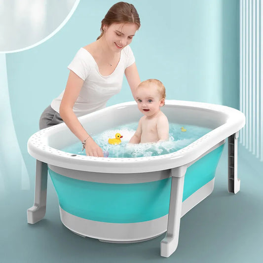 Une femme souriante baigne un bébé heureux dans une baignoire portable BABY PREMA avec des canards jouets et d'autres accessoires d'hygiène bébé flottant dans l'eau.