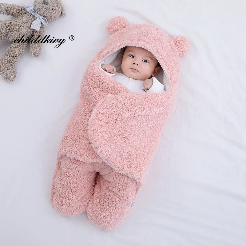 Un bébé douillet enveloppé dans une couverture Couverture Doux Bébé 0-7 Mois sur le thème de l'ours rose avec de jolies petites oreilles, allongé à côté d'une peluche et entouré des accessoires bébé essentiels de BABY-PREMA.