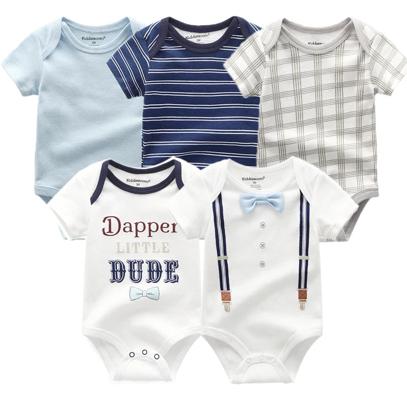 Cinq grenouillères pour bébé en coton doux : rayé bleu, marine et blanc, à carreaux, une avec le texte "Dapper Little Dude" et une avec un imprimé de fausses bretelles et nœud papillon, parfaites comme cadeau de naissance pour bébé. Présentation du Pack de 5 Bodies Coton Doux Bébé de BABY PREMA.