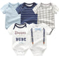 Cinq bodys bébé aux motifs différents : bleu clair, rayures bleues et blanches, carreaux gris et blancs, blanc avec texte "Dapper Little Dude" et blanc avec imprimé nœud papillon et bretelles. Ce Pack de 5 Bodies | Coton Doux Bébé de BABY PREMA faites un cadeau parfait pour les nouveaux parents pour compléter n'importe quelle garde-robe de bébé.