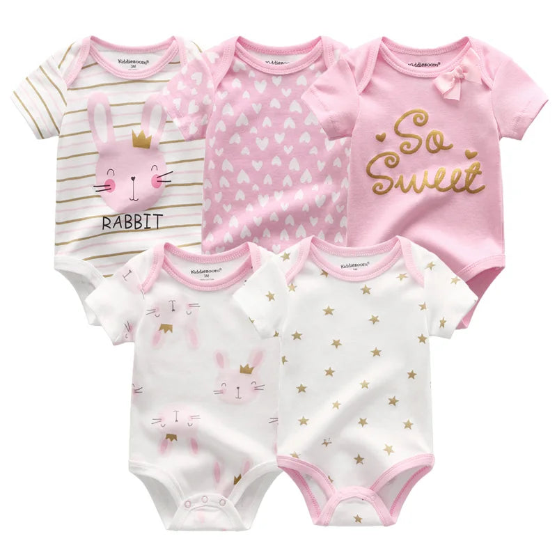 Cinq grenouillères pour bébé sur le thème rose sont disposées. Le Lot 5 Bodys Coton | Les imprimés manches courtes de BABY PREMA sont fabriqués à partir de bodys doux en coton, les motifs incluent des lapins, des cœurs, des étoiles et un avec le texte « So Sweet ». Ces tenues courtes à manches courtes comportent également des boutons-pression pratiques pour un changement facile.