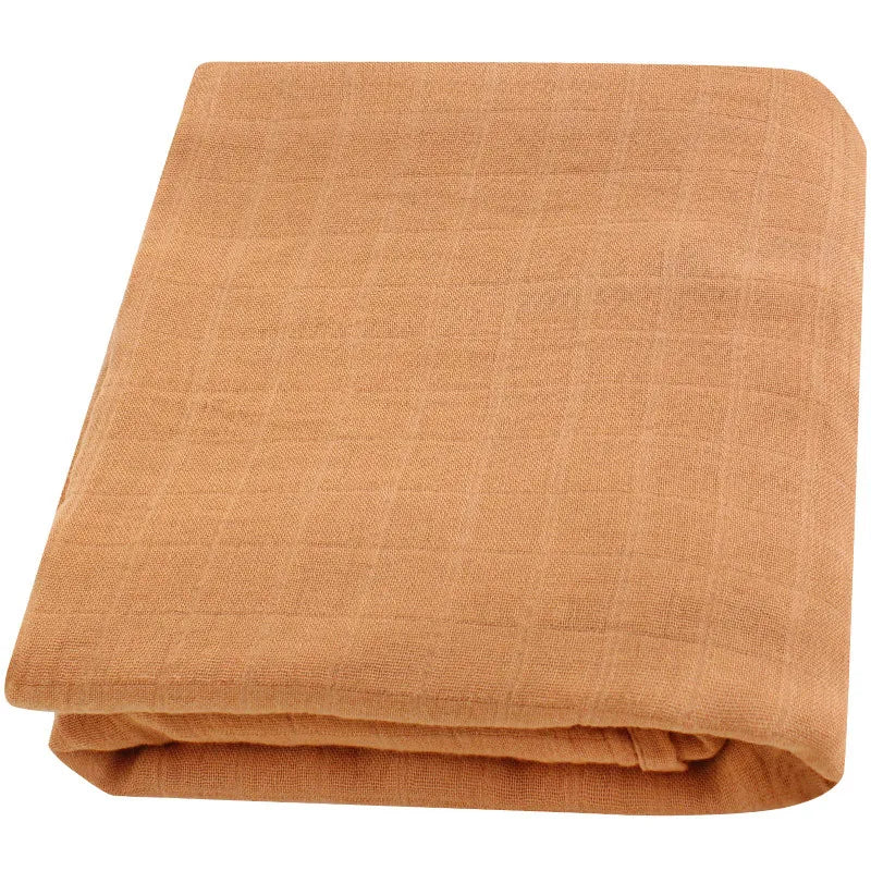 Une serviette en coton léger BABY PREMA soigneusement pliée, de couleur terre cuite, présentée sur un fond uni.