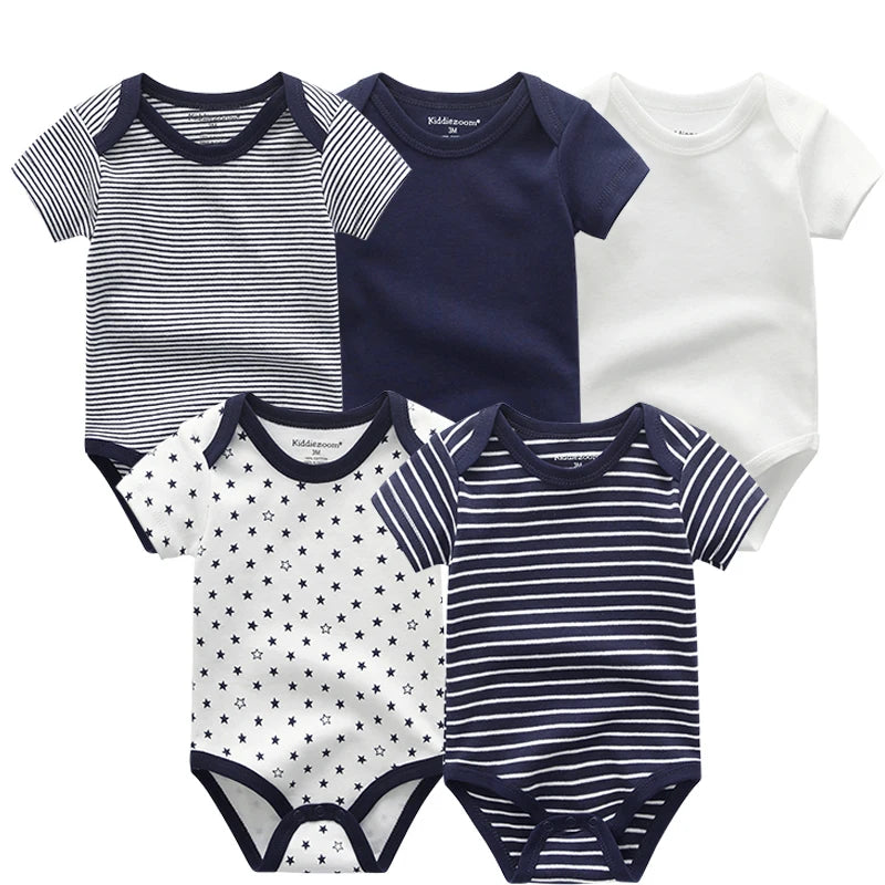 Cinq grenouillères pour bébé aux motifs et couleurs assortis : deux à rayures, un uni bleu marine, un uni blanc et un avec des étoiles. Le Pack de 5 Bodies Coton Doux Bébé de BABY PREMA constitue un parfait cadeau de naissance pour bébé.