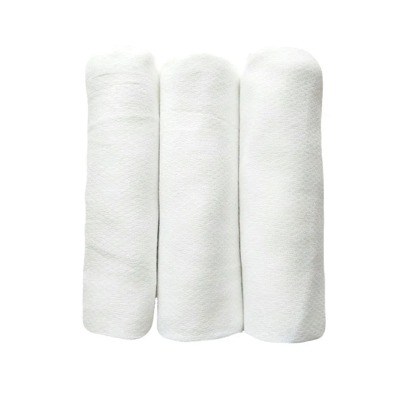 Trois serviettes BABY PREMA blanches enroulées, soigneusement disposées verticalement sur un fond blanc, conçues pour la peau délicate d'un bébé prématuré.