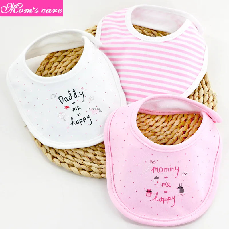 Trois Lot de 3 pièces Bavoirs Bébé de BABY-PREMA sont présentés sur un tapis circulaire tissé. Les bavoirs comprennent un blanc avec écrit "Daddy me Happy", un rose à rayures et un rose avec "Mommy me Happy" écrit dessus, le tout orné de petits motifs subtils. Fabriqués à partir de coton de haute qualité, ils portent l'étiquette "Mom's care" dans le coin supérieur gauche.